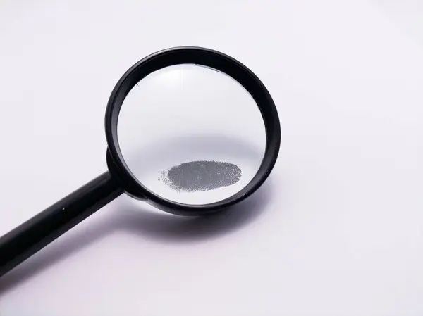 Beyaz bir yüzeyde parmak izi olan siyah saplı bir büyüteç.