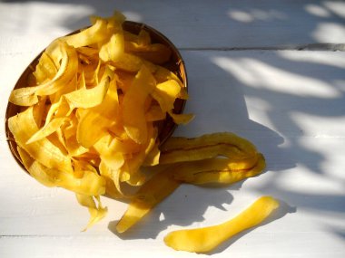 Beyaz ahşap arka planda sarı muz cipsi