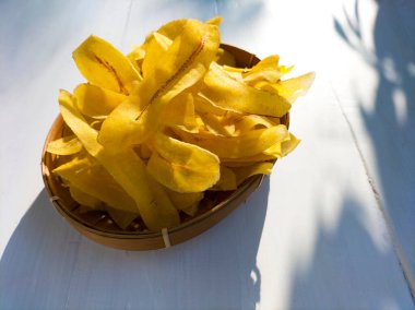 Beyaz ahşap arka planda sarı muz cipsi