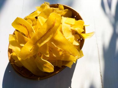 Beyaz ahşap arka planda sarı muz cipsi