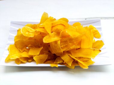 Beyaz ahşap arka planda sarı muz cipsi