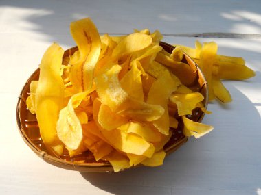 Beyaz ahşap arka planda sarı muz cipsi