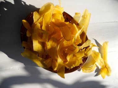 Beyaz ahşap arka planda sarı muz cipsi