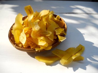 Beyaz ahşap arka planda sarı muz cipsi