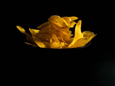 Siyah bir yüzeyde sarı muz cipsi