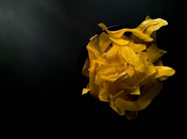 Siyah bir yüzeyde sarı muz cipsi