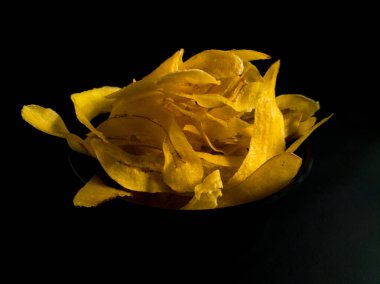 Siyah bir yüzeyde sarı muz cipsi