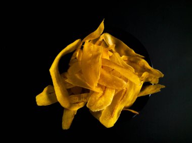 Siyah bir yüzeyde sarı muz cipsi