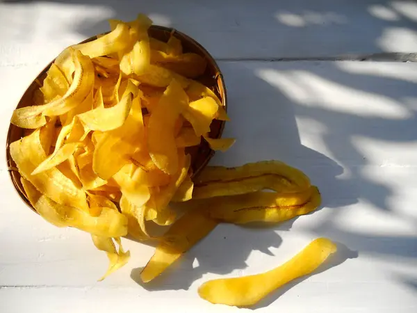 Beyaz ahşap arka planda sarı muz cipsi