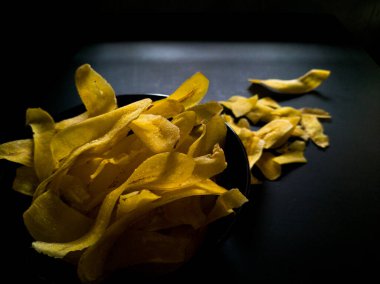 Siyah bir yüzeyde sarı muz cipsi