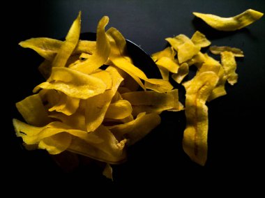 Siyah bir yüzeyde sarı muz cipsi