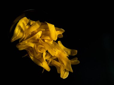 Siyah bir yüzeyde sarı muz cipsi