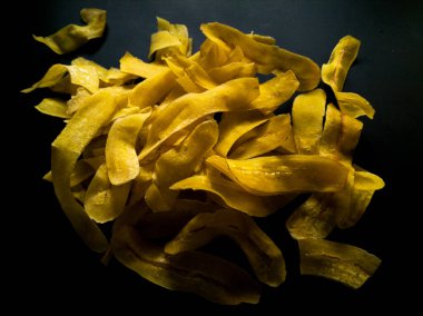 Siyah bir yüzeyde sarı muz cipsi