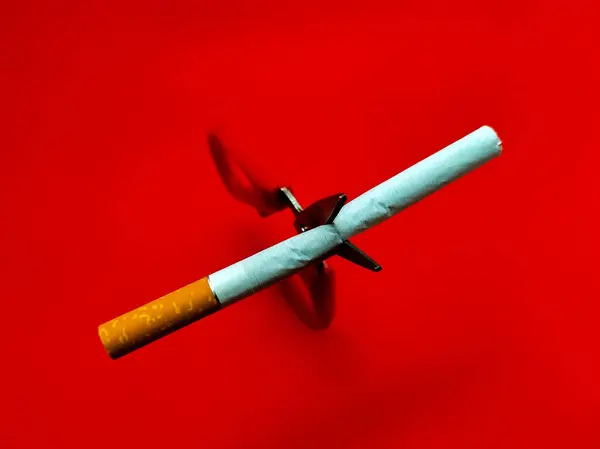 Kırık sigara ve makas kırmızı arka planda, sigara içmeyi bırak