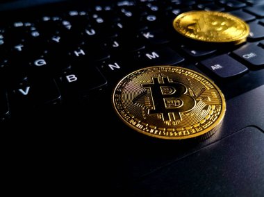 Altın bir Bitcoin para siyah bir bilgisayar klavyesine yerleştirilir. 
