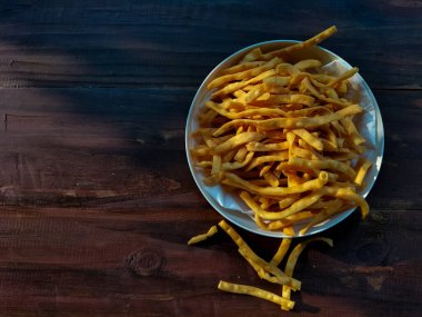 Tahta masaya yerleştirilmiş bir kase çıtır sarı atıştırmalık..