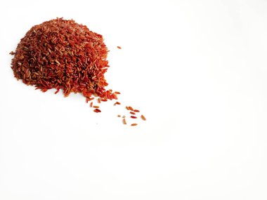 Pişmemiş bir yığın kırmızı pirinç taneciği beyaz bir yüzeye saçılmış.. 