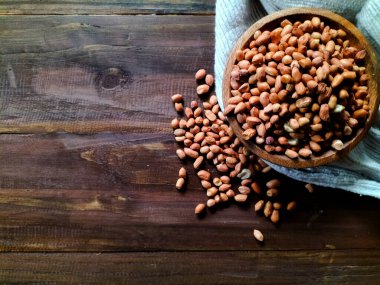 Kabuksuz fıstıklarla dolu ahşap bir kase, koyu ahşap bir yüzeyde oturur.. 