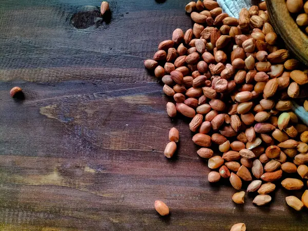 Kabuksuz fıstıklarla dolu ahşap bir kase, koyu ahşap bir yüzeyde oturur.. 