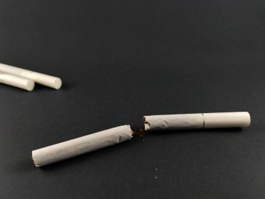 Kırık bir sigara karanlık bir yüzeye konur.