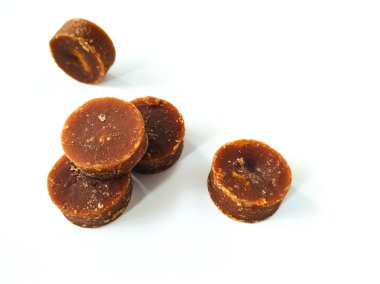 Yuvarlak kahverengi şeker parçaları beyaz bir yüzeye dizilmiştir.. 