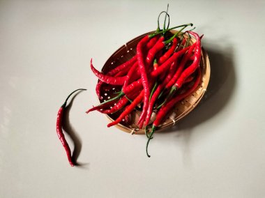 Kırmızı biberler kırmızı arka planda dokuma bambu sepetine konur.