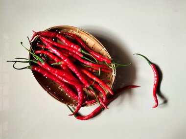 Kırmızı biberler kırmızı arka planda dokuma bambu sepetine konur.