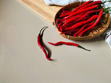 Kırmızı biberler kırmızı arka planda dokuma bambu sepetine konur.