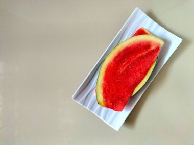 Dikdörtgen beyaz bir tabağa yerleştirilmiş karpuz. 