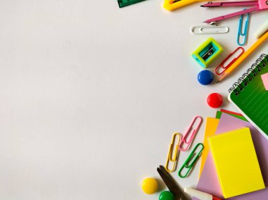 Beyaz bir yüzeye yerleştirilmiş çeşitli renkli okul malzemeleri. 