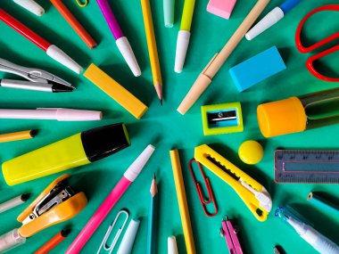 Canlı bir turkuaz arka planda rengarenk okul malzemeleri düzenleniyor. Okul konseptine dönelim. 