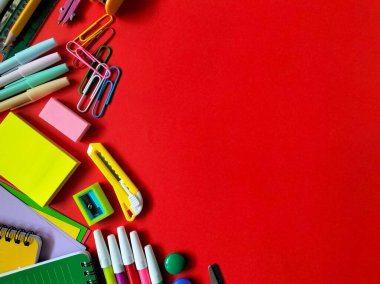 Canlı kırmızı arka planda çeşitli rengarenk okul malzemeleri. Okul konseptine dönelim. 