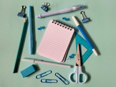 Açık mavi arka planda çeşitli okul malzemeleri düzenlenmiştir.