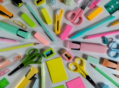 Beyaz bir yüzeye yerleştirilmiş çeşitli renkli okul malzemeleri.