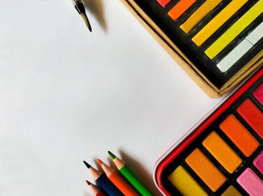 Beyaz bir yüzeye çeşitli okul malzemeleri yerleştirildi.