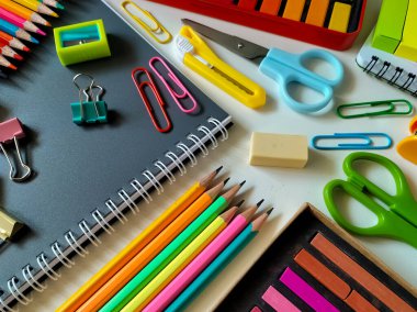 Beyaz bir yüzeye çeşitli okul malzemeleri yerleştirildi.