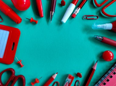 Kırmızı okul malzemeleri bir deniz mavisi yüzeyine yerleştirilmiştir..