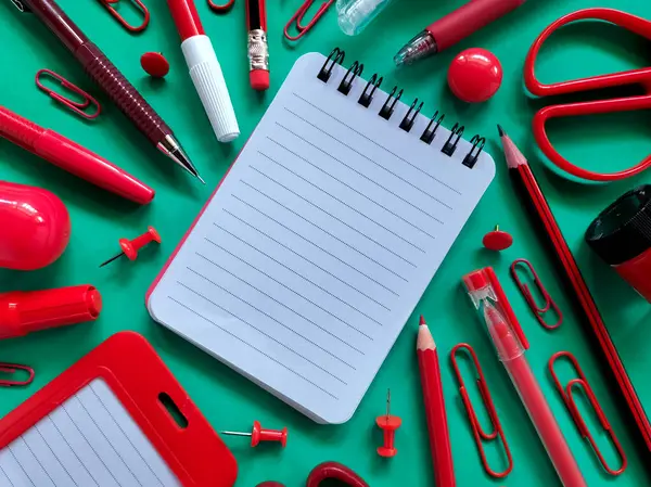 Kırmızı okul malzemeleri bir deniz mavisi yüzeyine yerleştirilmiştir..