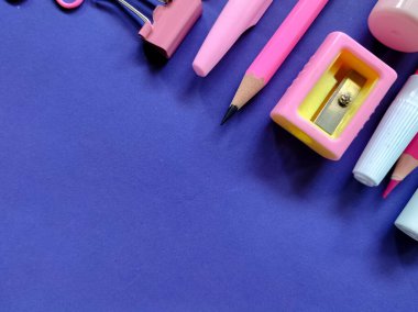 Mor yüzeyde çeşitli pembe okul malzemeleri var..