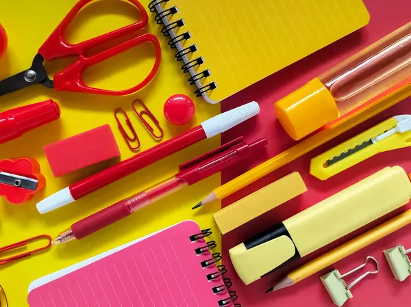 Kırmızı ve sarı okul malzemeleri düzgünce bir yüzeye yerleştirilmiş.. 