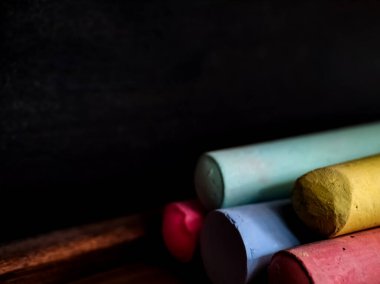 Tahta bir tahta çıkıntıda duran renkli tebeşir çubukları. 