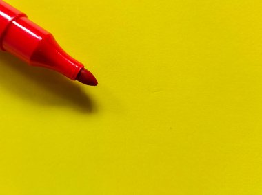 Close up of red marker with a rounded tip on a vibrant yellow background.