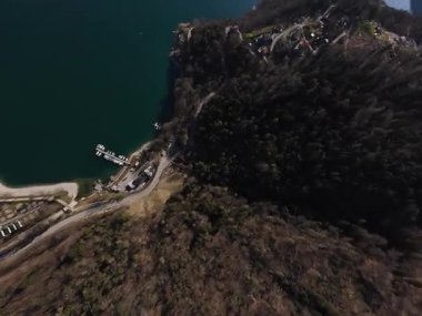 FPV İHA 'sının İtalyan gölü Ledro' daki bahar uçuşu, sabah güneşinin su üzerindeki parıltısı. Nisan başında çekildi..