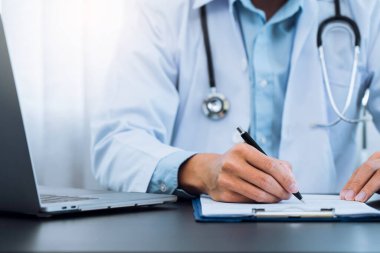 Doktor, elinde kalem tutarak hasta geçmişi listesini panoya yazıyor. İlaç ve tedavi hakkında..