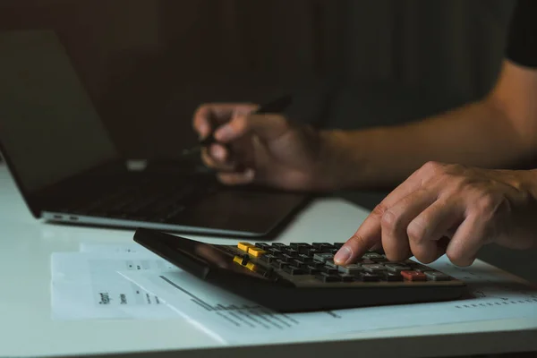 stock image Asian man is using a calculator to calculate his family's monthly miscellaneous expenses at his home.