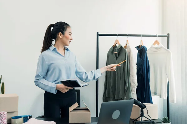 若いアジアの起業家は 顧客に販売する前に服をチェック — ストック写真