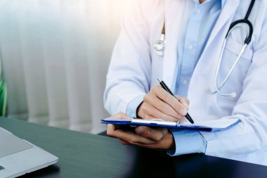 Doktor, elinde kalem tutarak hasta geçmişi listesini panoya yazıyor. İlaç ve tedavi hakkında..
