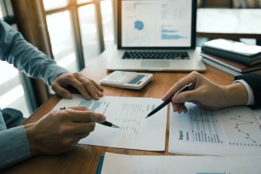 Ofis odasındaki bütçe toplantısında finansal planlama grafiği ve şirket bütçesini tartışan iki iş ortağı analiz stratejisi.