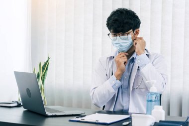 Ofisinde maske takan Asyalı erkek doktor..