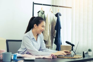 Genç Asyalı girişimciler gülerken bilgisayarın başında müşterilerle sohbet ediyorlar..